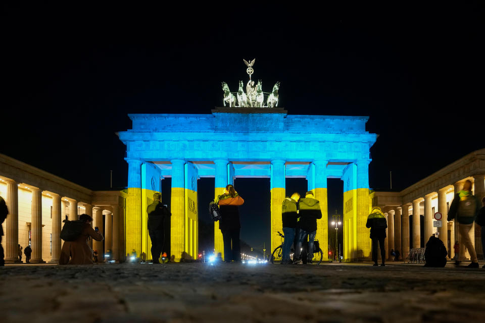 People look at the Brandenburg Gate after it was illuminated in the colors of the Ukrainian flag to show solidarity with the country during the tensions with Russia in Berlin, Feb. 23<span class="copyright">Markus Schreiber—AP</span>