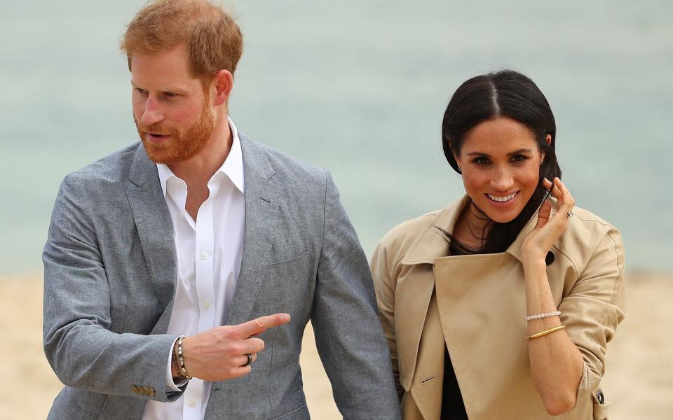 Prince Harry, Duke of Sussex wearing a Oura Health fitness tracker ring and Meghan, Duchess of Sussex walk at South Melbourne Beach on October 18, 2018