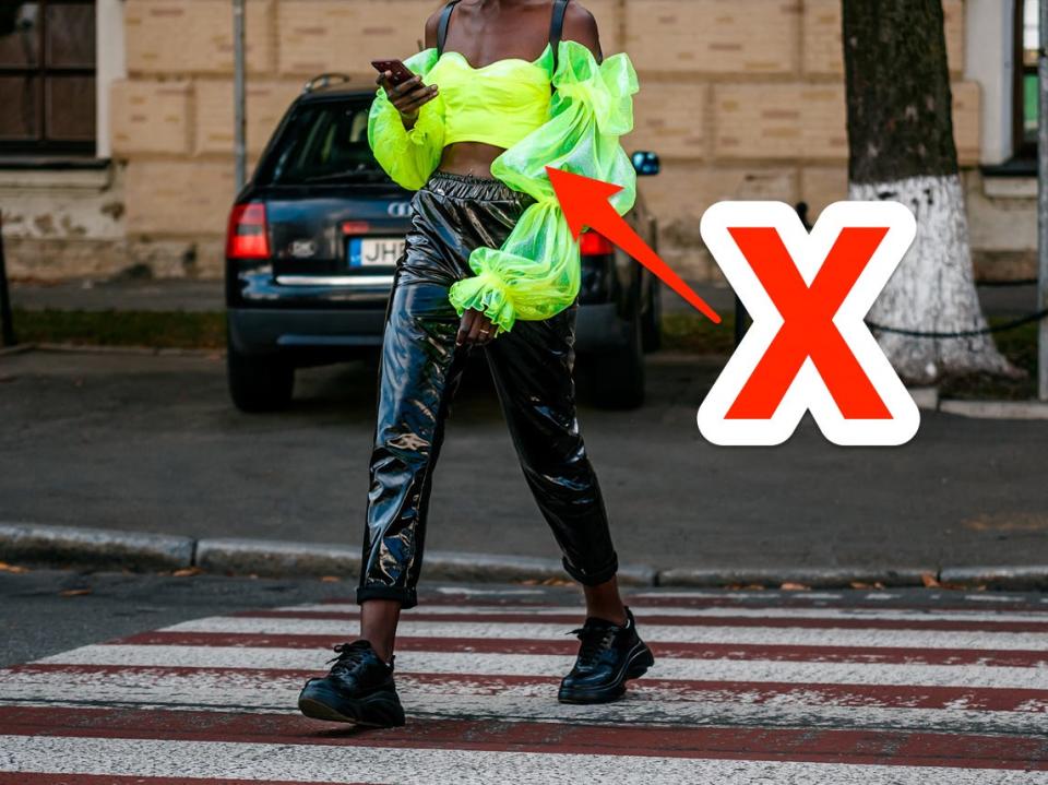 red x and arrow pointing at person crossing a street wearing yellow neon puffy blouse and black leather pants