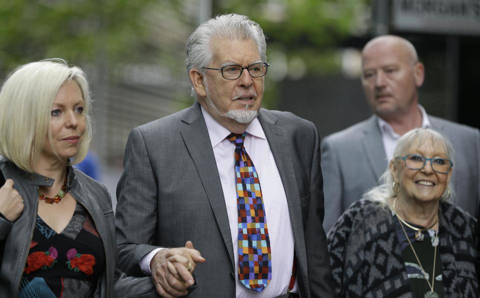 Veteran Australian-British entertainer Rolf Harris who is accused of indecent assault arrives with his wife Alwen Hughes, right, and daughter Bindi at Southwark Crown Court in London, Friday, May 9, 2014.The 84-year-old is charged with indecently assaulting four girls between 1968 and 1986. The girls ranged in age from 7 or 8 to 19. Harris denies the charges. (AP Photo/Kirsty Wigglesworth)