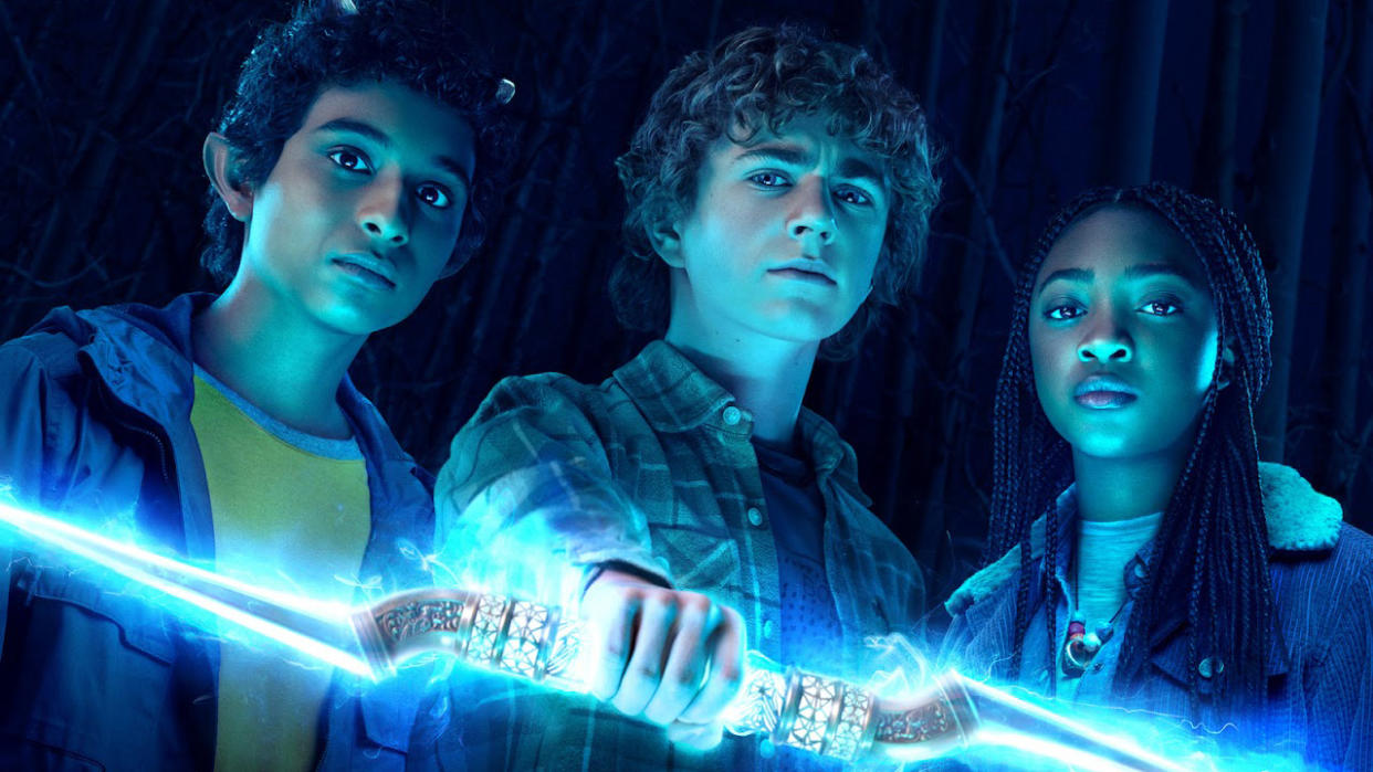  A promotional image showing Grover, Percy holding a lightning bolt, and Annabeth in Percy Jackson and the Olympians. 