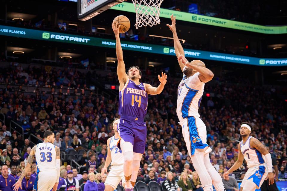 Phoenix Suns guard Landry Shamet (14) makes a shot against Washington Wizards forward Taj Gibson (67) at Footprint Center on Tuesday, Dec. 20, 2022.