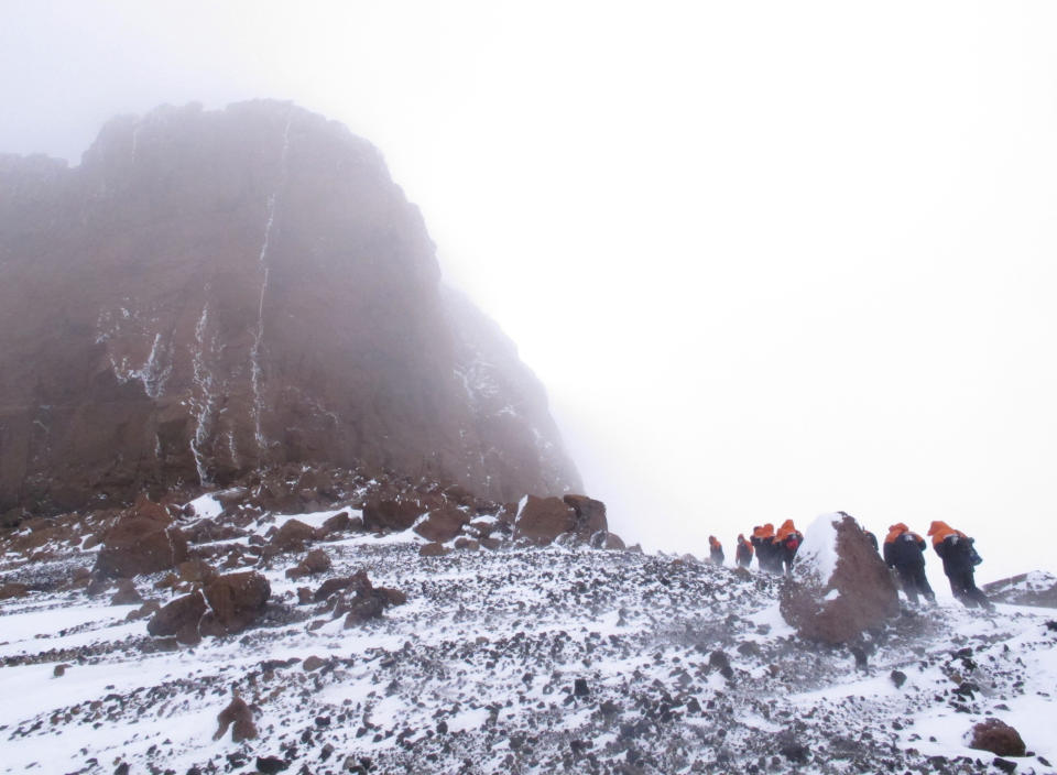 In this Jan. 20, 2013 photo, tourists scale Crater Hill toward Castle Rock on Ross Island, Antarctica. Tourism is rebounding here five years after the financial crisis stifled what had been a burgeoning industry. And it’s not just retirees watching penguins from the deck of a ship. Visitors are taking tours inland and even engaging in “adventure tourism” like skydiving and scuba diving under the ever-sunlit skies of a Southern Hemisphere summer. (AP Photo/Rod McGuirk)