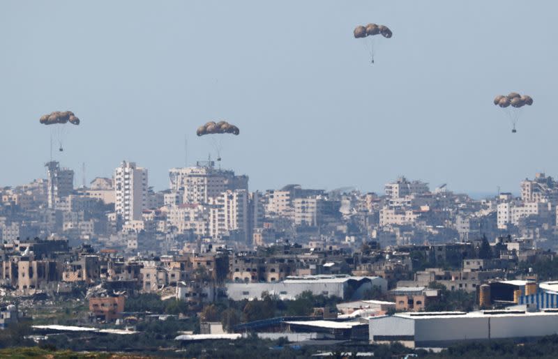 Humanitarian aid falls through the sky towards the Gaza Strip, as seen from Israel's border with Gaza