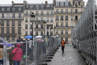 Pedestrians walk across a sidewalk opened to foot traffic on the Pont Royal, or Royal Bridge, as workers begin dismantling grandstands used in the opening ceremonies, at the 2024 Summer Olympics, Saturday, July 27, 2024, in Paris, France. (AP Photo/Rebecca Blackwell)