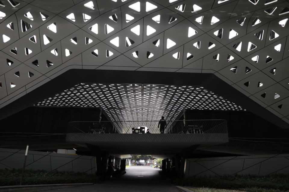 A security guard walks outside theater halls at the Cineteca Nacional, Mexico's film archive, in Mexico City, Wednesday, Aug. 12, 2020. After being closed for nearly five months amidst the ongoing coronavirus pandemic, movie theaters in the capital reopened Wednesday at 30% capacity. (AP Photo/Rebecca Blackwell)