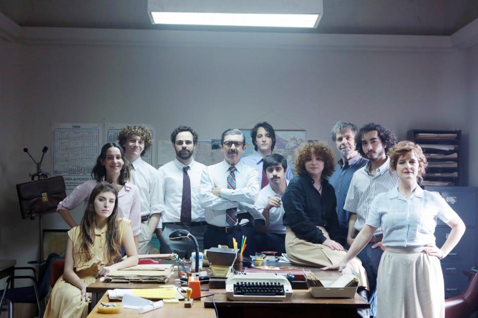 The cast stands around a table