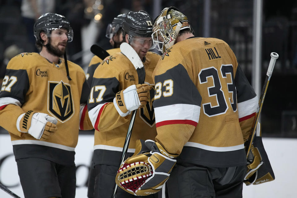 Vegas Golden Knights defenseman Ben Hutton (17) and goaltender Adin Hill (33) celebrate after defeating the Anaheim Ducks in an NHL hockey game Saturday, Oct. 14, 2023, in Las Vegas. (AP Photo/John Locher)