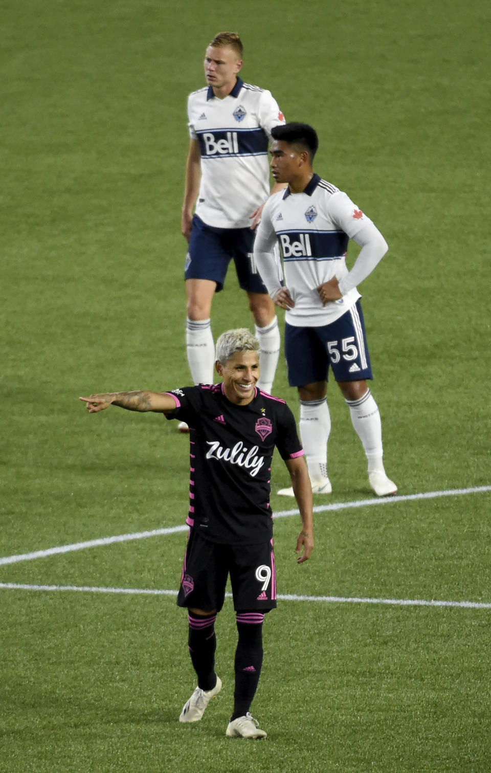 Seattle Sounders forward Raul Ruidiaz, bottom, celebrate after the Sounders scored a goal as Vancouver Whitecaps midfielder Michael Baldisimo, center, and midfielder Andy Rose, top, stand nearby during the second half of an MLS soccer match in Portland, Ore., Tuesday, Oct. 27, 2020. (AP Photo/Steve Dykes)