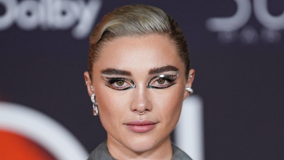 Florence Pugh with silver reflective eye stickers in backless grey dress 