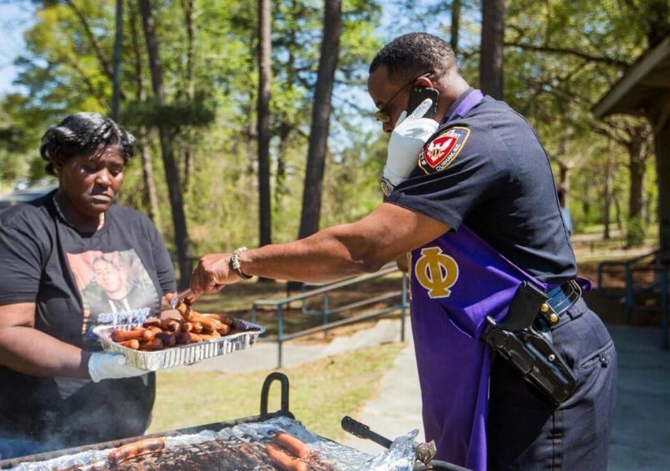 Georgetta Ray, left, and Durham Police Department Capt. Daniel Edwards grill hot dogs Tuesday to serve to residents of McDougald Terrace. Durham police officers, led by Edwards, have been gathering with the community for lunch every Tuesday since the beginning of the year in hopes of improving their relationship.