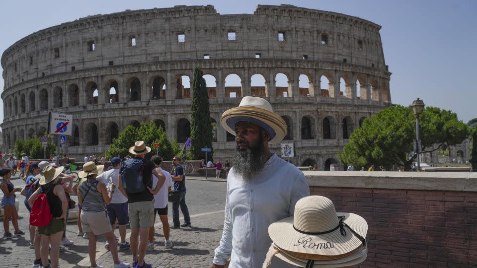 A street vendor walks with hats in front of the Colosseum in Rome, Monday, July 17, 2023. - Gregorio Borgia/AP