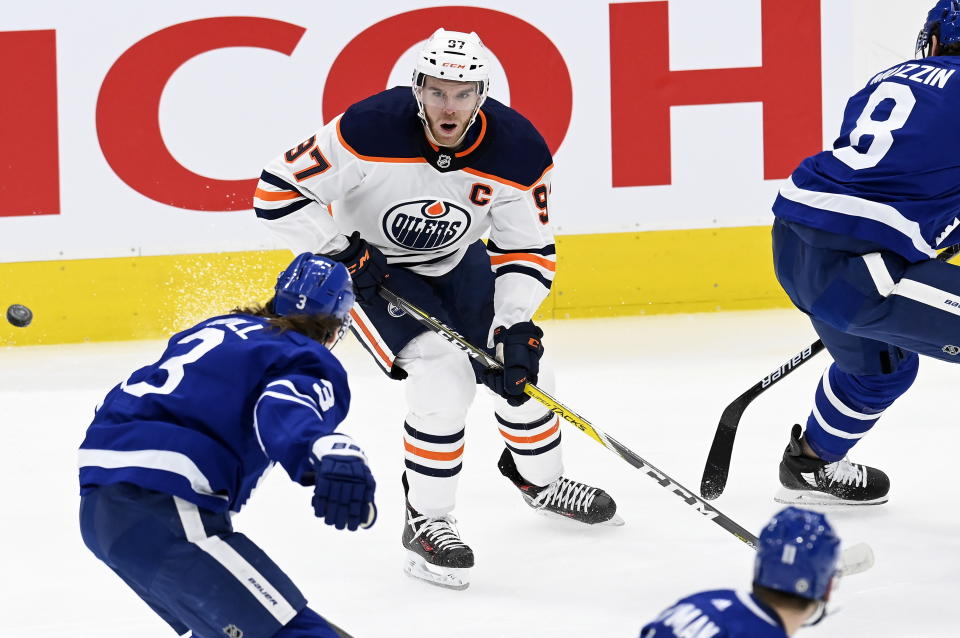 Edmonton Oilers center Connor McDavid (97) looks on as the puck flies between him and Toronto Maple Leafs defenseman Justin Holl (3) during first-period NHL hockey game action in Toronto, Saturday, March 27, 2021. (Frank Gunn/The Canadian Press via AP)