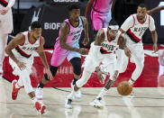 Portland Trail Blazers forward Robert Covington, second from right, leads a fast break with guard CJ McCollum, left, and forward Norman Powell, right, as Miami Heat forward Jimmy Butler trails behind during the second half of an NBA basketball game in Portland, Ore., Sunday, April 11, 2021. (AP Photo/Craig Mitchelldyer)