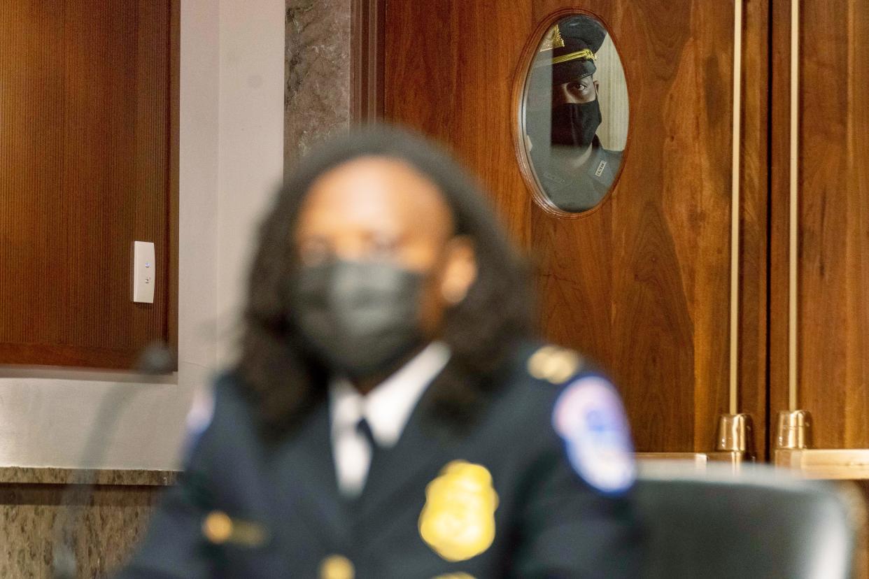 An officer looks through a window as Capitol Police Capt. Carneysha Mendoza, foreground, prepares to speak at a Senate Homeland Security and Governmental Affairs & Senate Rules and Administration joint hearing on Capitol Hill, Washington, Tuesday, Feb. 23, 2021, to examine the January 6th attack on the Capitol.