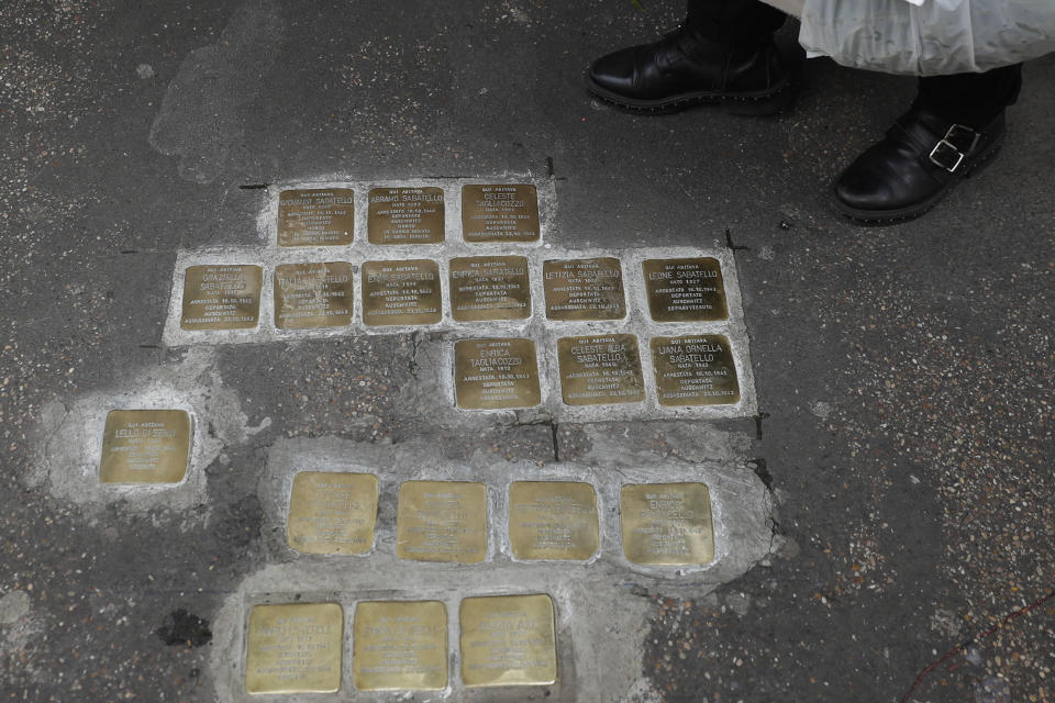 A woman stands by stumbling stones, engraved with names of Jews killed by the Nazis, in Rome's Ghetto Jewish neighborhood, Wednesday, Jan. 27, 2021, on the occasion of International Day of Commemoration in memory of the victims of the Holocaust and the 76th anniversary of the liberation of the Nazi German extermination camp Auschwitz-Birkenau. On Oct. 16, 1943 German occupation soldiers gathered more than 1,000 Jewish men, women and children from their homes in the Roman Ghetto and sent them to Auschwitz. (AP Photo/Gregorio Borgia)