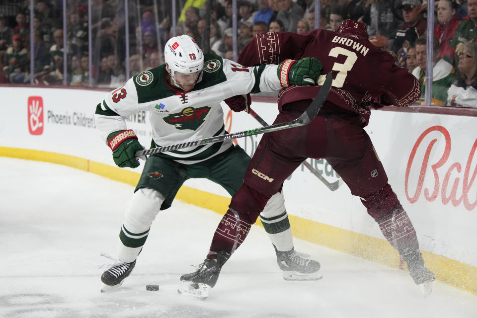 Minnesota Wild center Sam Steel (13) and Arizona Coyotes defenseman Josh Brown fight for the puck during the third period of an NHL hockey game, Sunday, March 12, 2023, in Tempe, Ariz. Arizona won 5-4 in overtime. (AP Photo/Rick Scuteri)