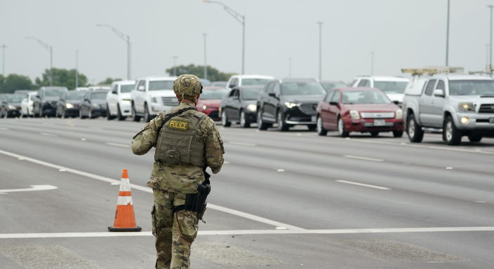 A military policeman walks past traffic outside of a JBSA-Lackland Air Force Base gate, Wednesday, June 9, 2021, in San Antonio. The Air Force was put on lockdown as police and military officials say they searched for two people suspected of shooting into the base from outside. (AP Photo/Eric Gay)