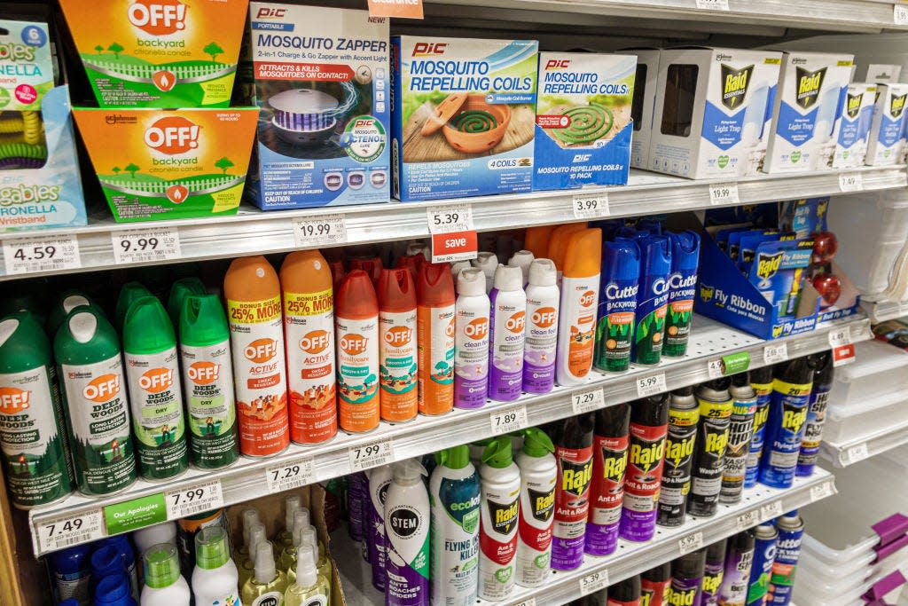 Several bottles of insect repellants in aerosol cans on a grocery store shelf