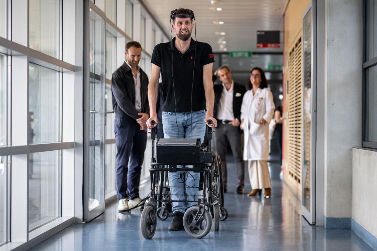 Gert-Jan Oskam, paralyzed from the waist down, holds on to a walker as he stands in a hallway.