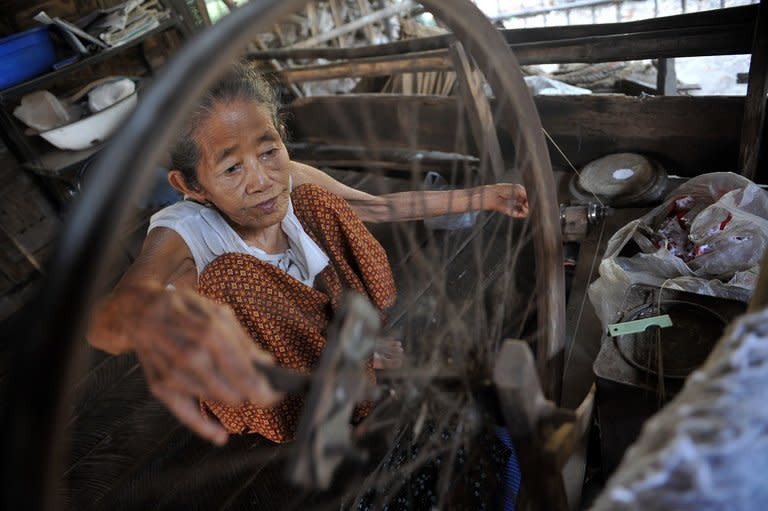 An elderly woman uses an old weaving loom to make cotton clothes at her house in Mawlamyine, Myanmar's Mon state, on March 14, 2013. Myanmar's southeast Mon state is a place bereft of its young, who have flooded overseas in search of work