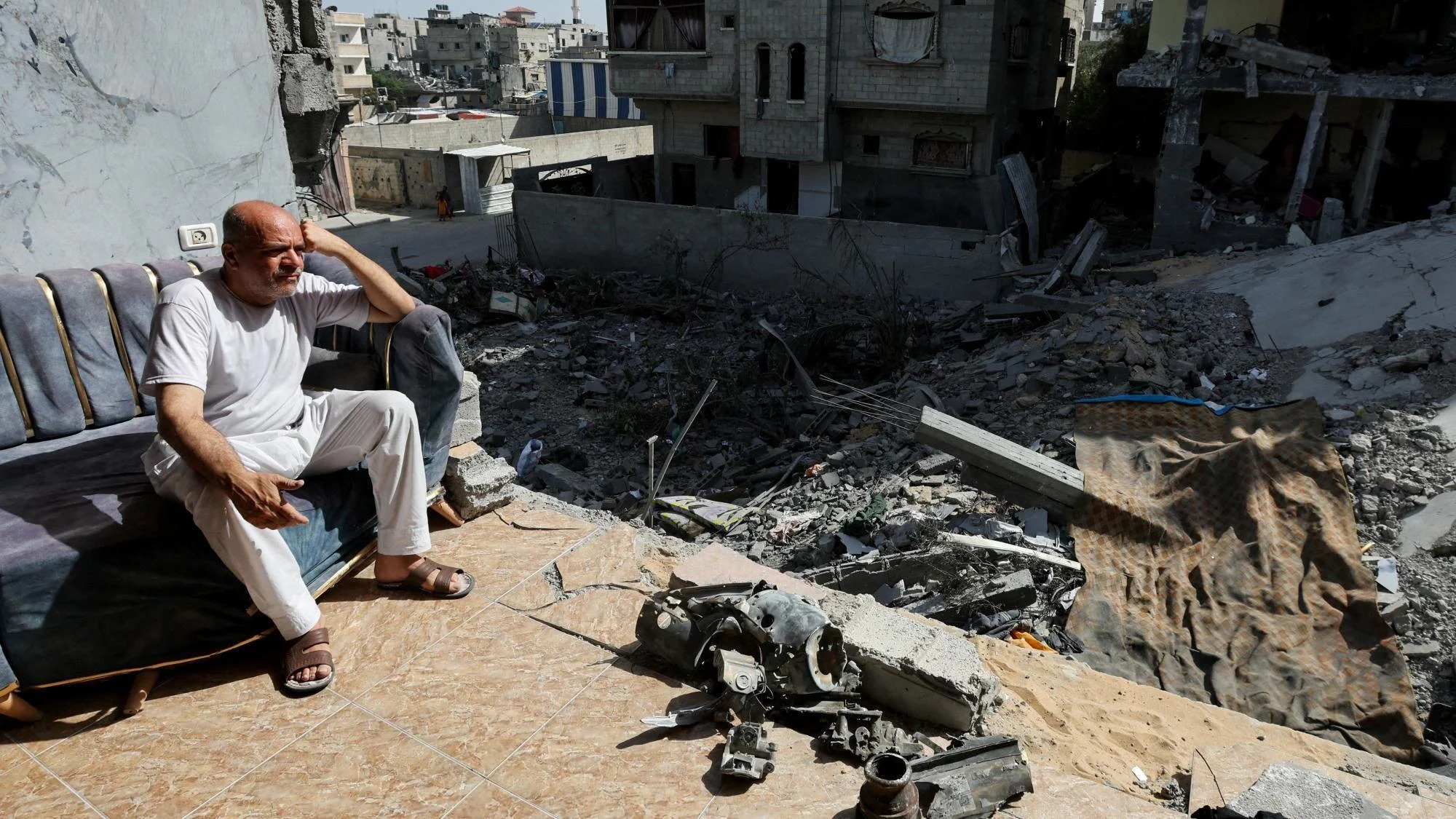 A man sits inside a ruined building following an Israeli military operation that rescued four hostages held by Hamas in Nuseirat refugee camp, in central Gaza (15 June 2024)