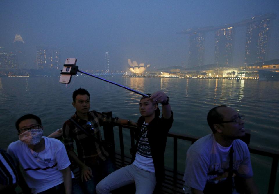 Tourists take selfies as they pass along the haze-shrouded Marina Bay in a bum boat in Singapore