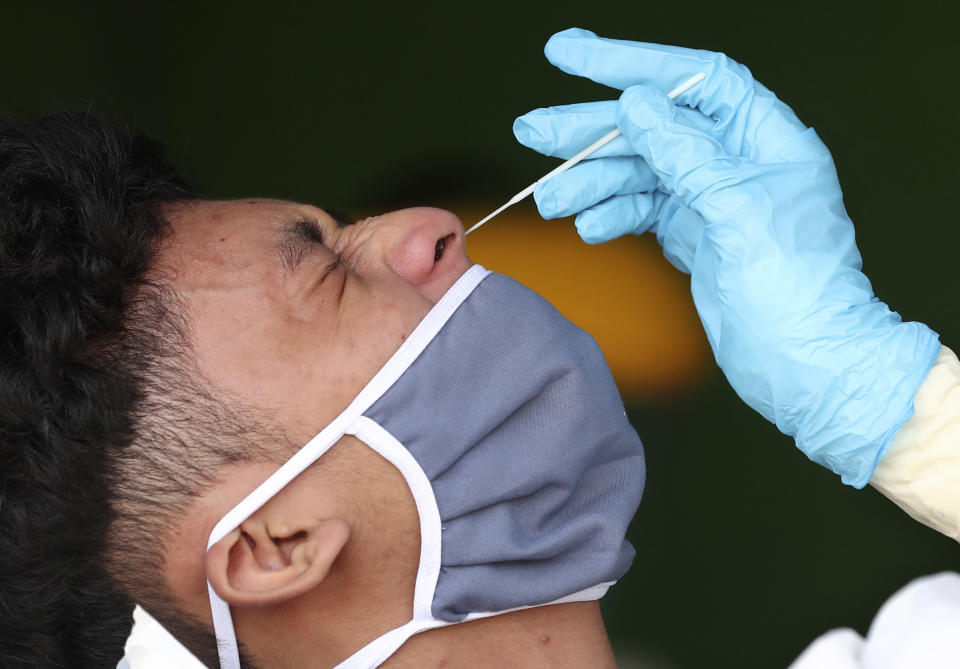 A man reacts as a health worker collects nasal swab samples from him during a mass test for the new coronavirus at a market in Jakarta, Indonesia, Thursday, June 25, 2020. (AP Photo/Tatan Syuflana)