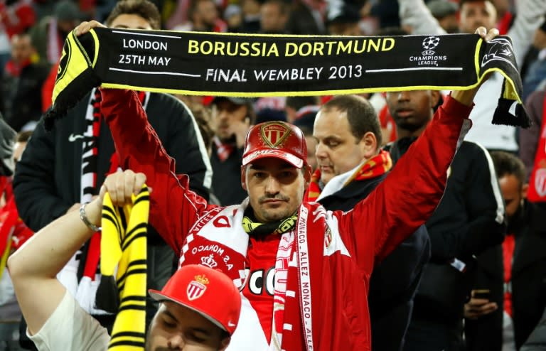 Monaco supporters with Borussia scarves react in the stadium after the match was postponed amid an explosion near the bus of Borussia Dortmund prior to the UEFA Champions League 1st leg quarter-final football match on April 11, 2017