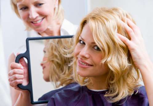 hairdresser holding up mirror for woman with new haircut