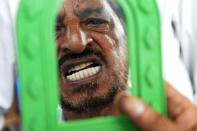 A customer examines a new set of dentures during a visit to a street dentist at K.R. Market bus stand in Bangalore