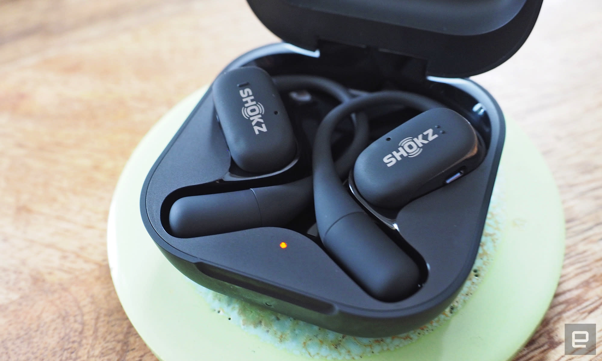 Close-up images of the Shokz OpenFit open-ear buds in grey with the charging case.