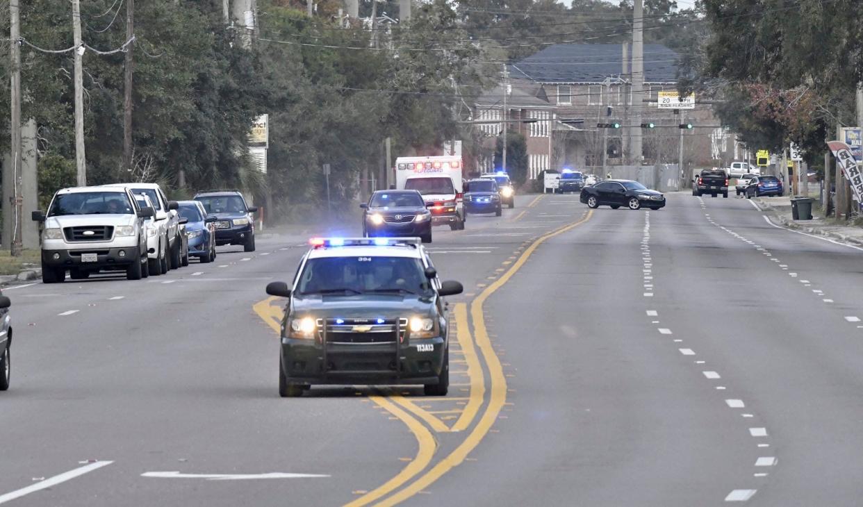 Police cars escort an ambulance after a shooter opened fire inside the Pensacola Air Base in Florida on Friday, Dec. 6, 2019.