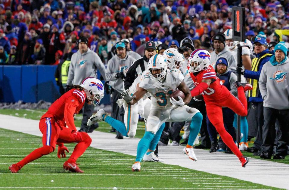 Miami Dolphins running back Raheem Mostert (31) runs the football against Buffalo Bills safety Damar Hamlin (3) and Bills cornerback Dane Jackson (30) during fourth quarter of an NFL football game at Highmark Stadium on Saturday, December 17, 2022 in Orchard Park, New York.