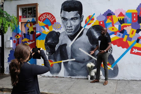 A man has his photograph taken near a makeshift memorial to the late Muhammad Ali in New York, U.S., June 4, 2016. REUTERS/Lucas Jackson