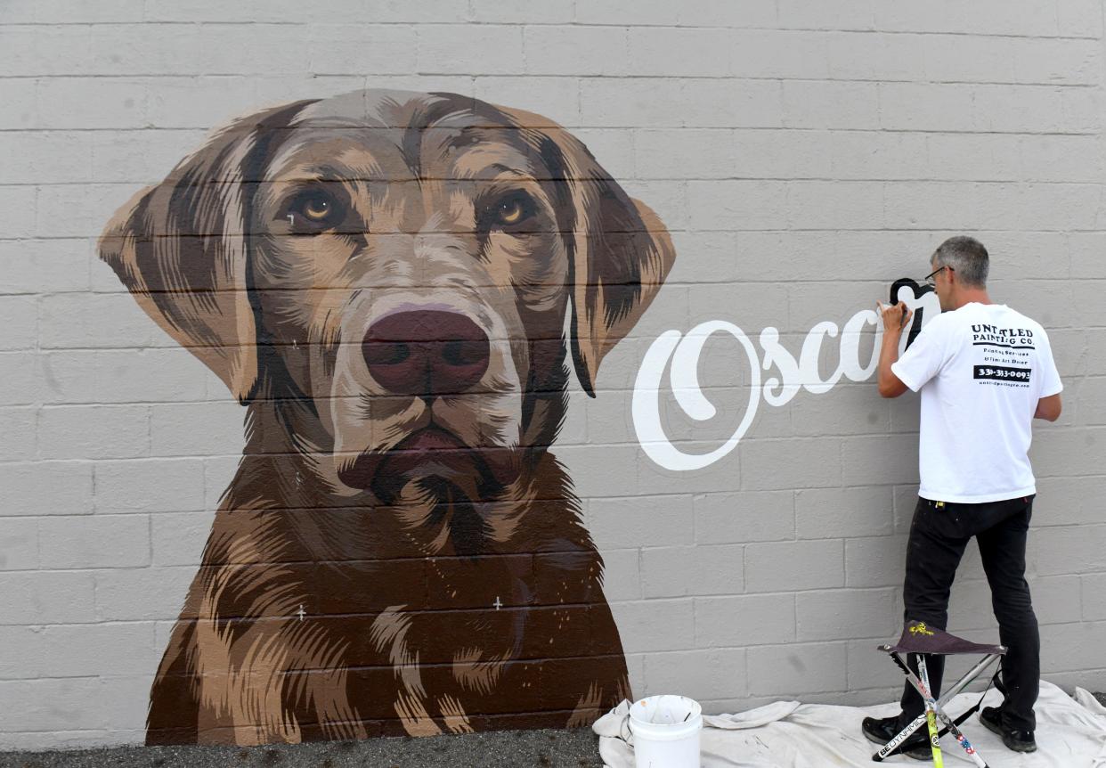 Artist and owner of Untitled Painting Co. Josh Humm creates a mural of TJ Sliman’s dogs on the side of his family business, Meyers Lake Beverage and Drive Thru in Canton.