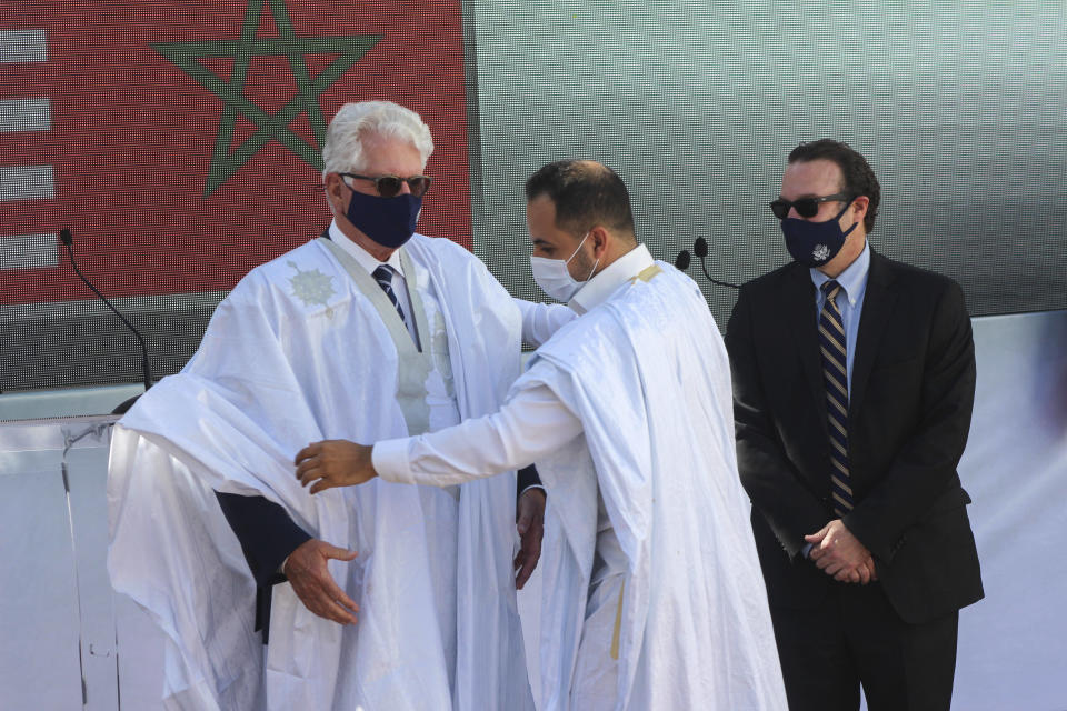 US Ambassador to Morocco David T. Fischer, left, is presented a Sahraoui traditional wear after arriving in Dakhla, Morocco-administered Western Sahara, Sunday Jan. 10, 2021. The highest ranking U.S. diplomat for North Africa and the Middle East, as well as the first ever U.S Ambassador, traveled Sunday to the Morocco-administered Western Sahara city of Dakhla, laying the groundwork for the United States to set up a consulate in the disputed territory. (AP Photo/Noureddine Abakchou)