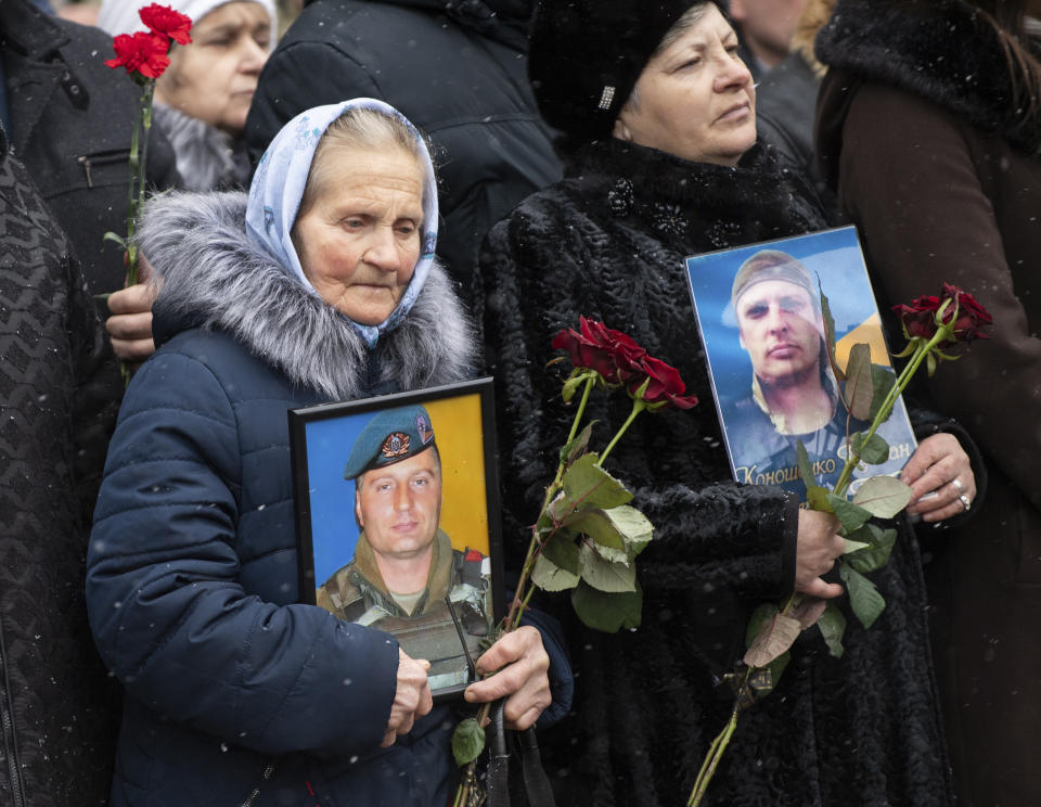 Relatives hold photos of the soldiers killed as they defended Donetsk airport in 2014-15 in a war conflict with Russia-backed separatists during a commemorating ceremony in Kyiv, Ukraine, Monday, Jan. 20, 2019. Ukraine has asked the Organization for Security and Cooperation in Europe to expand its monitoring mission in the country, Foreign Minister Vadym Prystaiko said Monday after a meeting with the organization's chairman. (Ukrainian Presidential Press Office via AP)