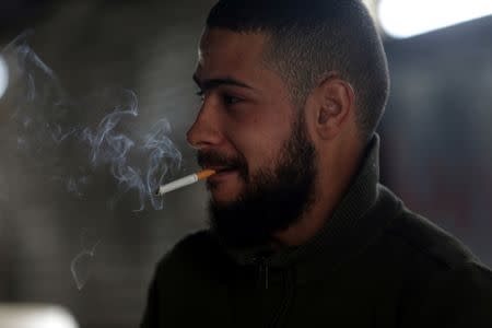 Mutassim al-Misrati, a Benghazi-local who lost his leg during a three-year war in the city, smokes a cigarette as he works at a fish market in Benghazi, Libya December 27, 2017. Picture taken December 27, 2017. REUTERS/Esam Omran Al-Fetori