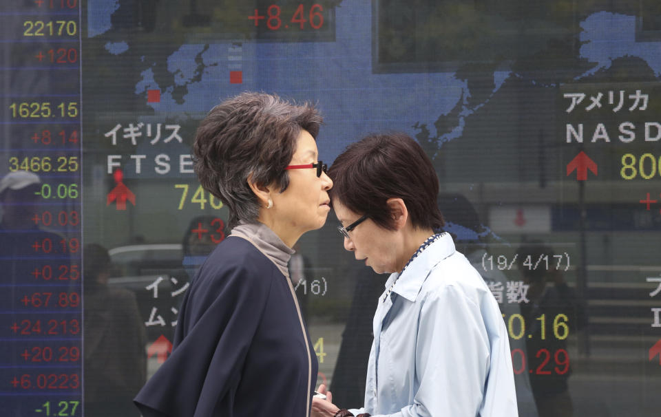 People walk by an electronic stock board of a securities firm in Tokyo, Wednesday, April 17, 2019. Shares were mixed in a narrow range Wednesday as China announced its economy grew at a 6.4 percent annual pace in the last quarter. (AP Photo/Koji Sasahara)