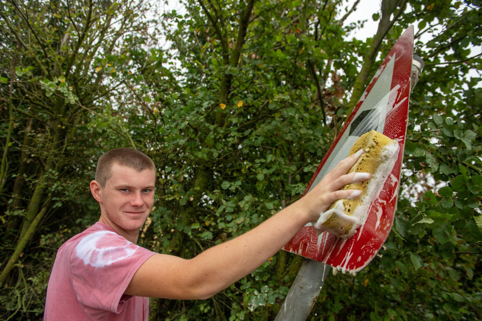 A teenage boy annoyed by road signs left dirty and hedges overgrown during lockdown has become a local hero after going on a mission to clean them all up. Joseph Beer, 15, noticed dozens of neglected street signs and hedgerows whilst out on his daily walks with mum Lisa, 52. He soon decided he wanted to clean up the streets - and with the help of dad Mark, 56, he rigged up a trailer to fix to the back of his bike, and started peddling around the streets near his house. Almost every day, Joseph, from Chatteris, Cambs., has headed off on his bike, towing a bucket of soapy water, some sponges, and garden tools, including hedgecutters and a rake, in the trailer.

His efforts have seen him clean up street name signs that have been left almost unreadable due to moss growing over them, such as Wilburton Road in nearby Ely.