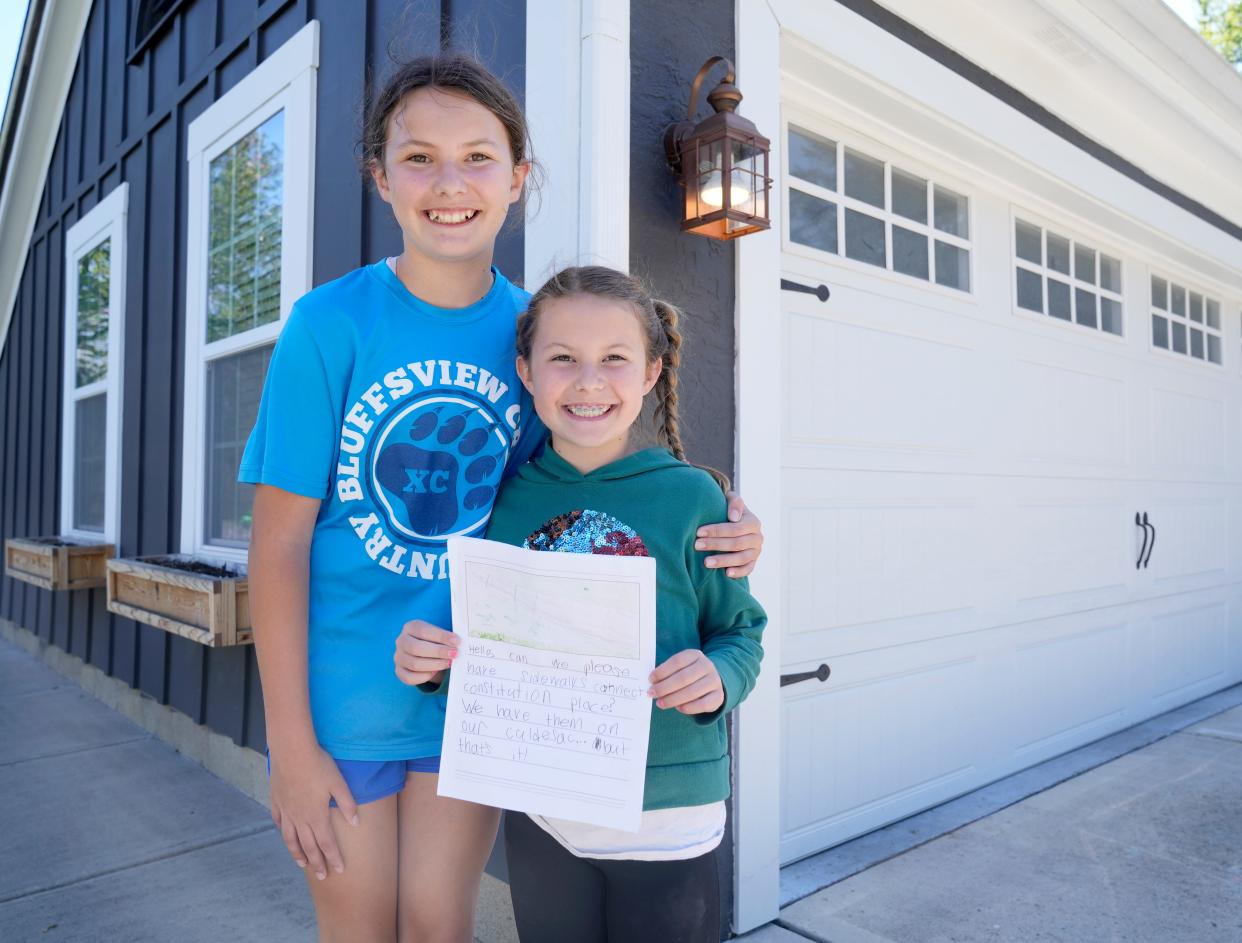 Sisters Lucy Honigford, 10, left, and Hazel Honigford, 8, created a book of pictures and words asking the city of Columbus to put sidewalks in their neighborhood on the Northwest Side near Worthington and Olentangy River Road.