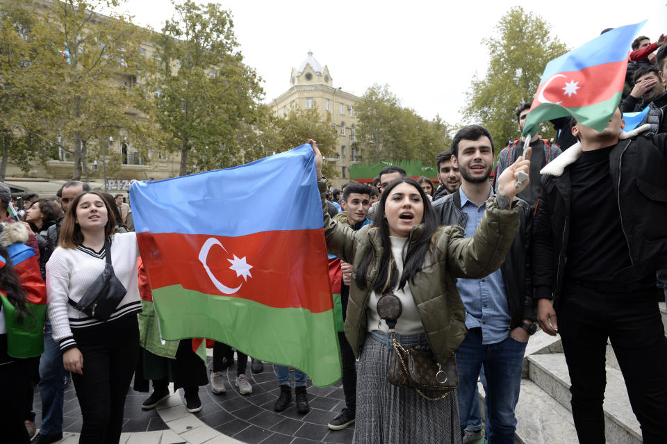 Azerbaijanis celebrate waving national flags in Baku, Azerbaijan, Tuesday, Nov. 10, 2020. Armenia and Azerbaijan announced an agreement early Tuesday to halt fighting over the Nagorno-Karabakh region of Azerbaijan under a pact signed with Russia that calls for deployment of nearly 2,000 Russian peacekeepers and territorial concessions. (AP Photo)