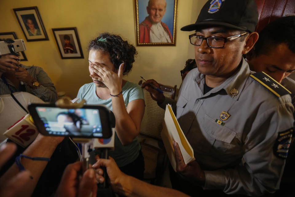Escorted by a prison official, opposition member María Adilia Peralta Cerratos cries when she talks to the press during her return home after being in prison, in Masaya, Nicaragua, Monday, May 20, 2019. Peralta Cerratos is one of 100 prisoners the Nicaraguan government released Monday in a form of house arrest, including three human rights activists. (AP Photo/Alfredo Zuniga)
