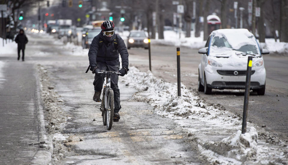 A cyclist makes his way down a bike path Tuesday, Feb. 17, 2015, in Montreal, despite frigid temperatures and slippery roadways. Bicycle commuting is common even in the city’s brutal winters, thanks to an expanding network of paths safely separated from traffic. (Paul Chiasson/The Canadian Press via AP)