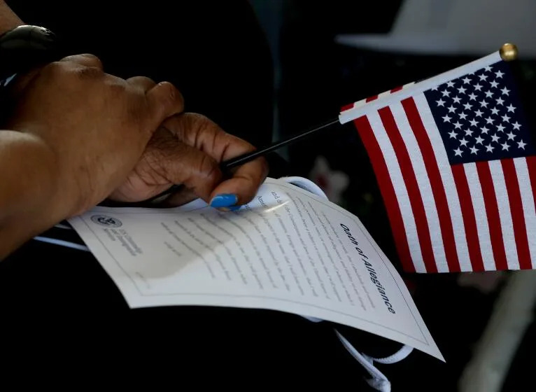 LOS ANGELES, CA - JULY 01:. An immigrant holds a flag and the Oath of Allegiance during a U.S. citizenship ceremony for naturalized citizens aboard the battleship USS Iowa in the Port of Los Angeles on Thursday, July 1, 2021. The event newly minted American citizens from Asia, Africa, Europe and the Americas. (Luis Sinco / Los Angeles Times)
