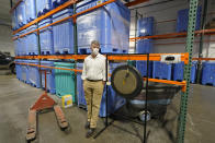 Micah Truman, CEO of Return Home, a company that composts human remains into soil, poses for a photo, Wednesday, Sept. 15, 2021, in Auburn, Wash., south of Seattle. At right is a gong that is struck by workers each time a body is placed into the vessel that holds it during the composing process, which is part of a ritual initiated by Truman to preserve the individual dignity of each person trusted to his company's care. Behind him are vessels where remains are kept during the second month of the two-month composing process. Earlier in September, Colorado became the second state after Washington to allow human body composting, and Oregon will allow the practice beginning next July. (AP Photo/Ted S. Warren)