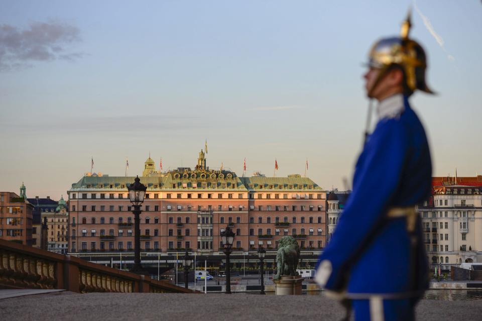 A Palace guard stands in front of the Royal Palace while the sun sinks over the Grand Hotel in downtown Stockholm, Sweden Tuesday Sept.3, 2013, on the eve of the two-day visit by U.S. President Barack Obama. The President is believed to be staying at this hotel. (AP photo / TT News Agency / Henrik Montgomery) ** SWEDEN OUT **