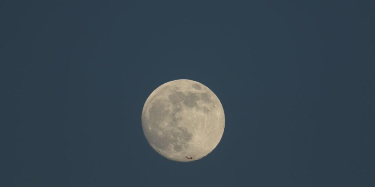 the magnificent wolf moon, the first full moon of january 2022 seen from kent, uk an aeroplane can been seen flying over the bottom of the moon