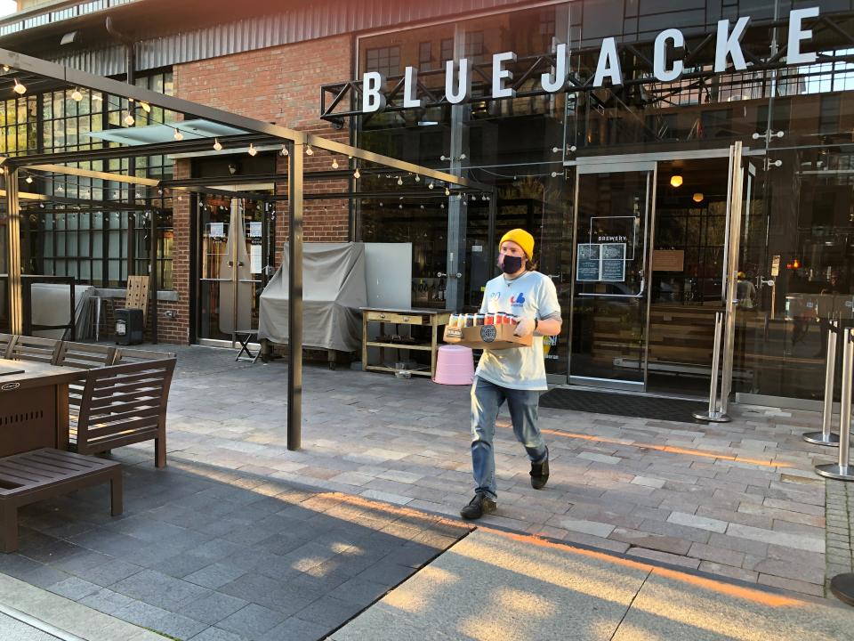 Conor Provost of Bluejacket brewery in Washington, D.C., puts beer in a car in April 2020. The brewpub began offering curbside pickup and delivery of beer and food at the onset of the coronavirus shutdown.